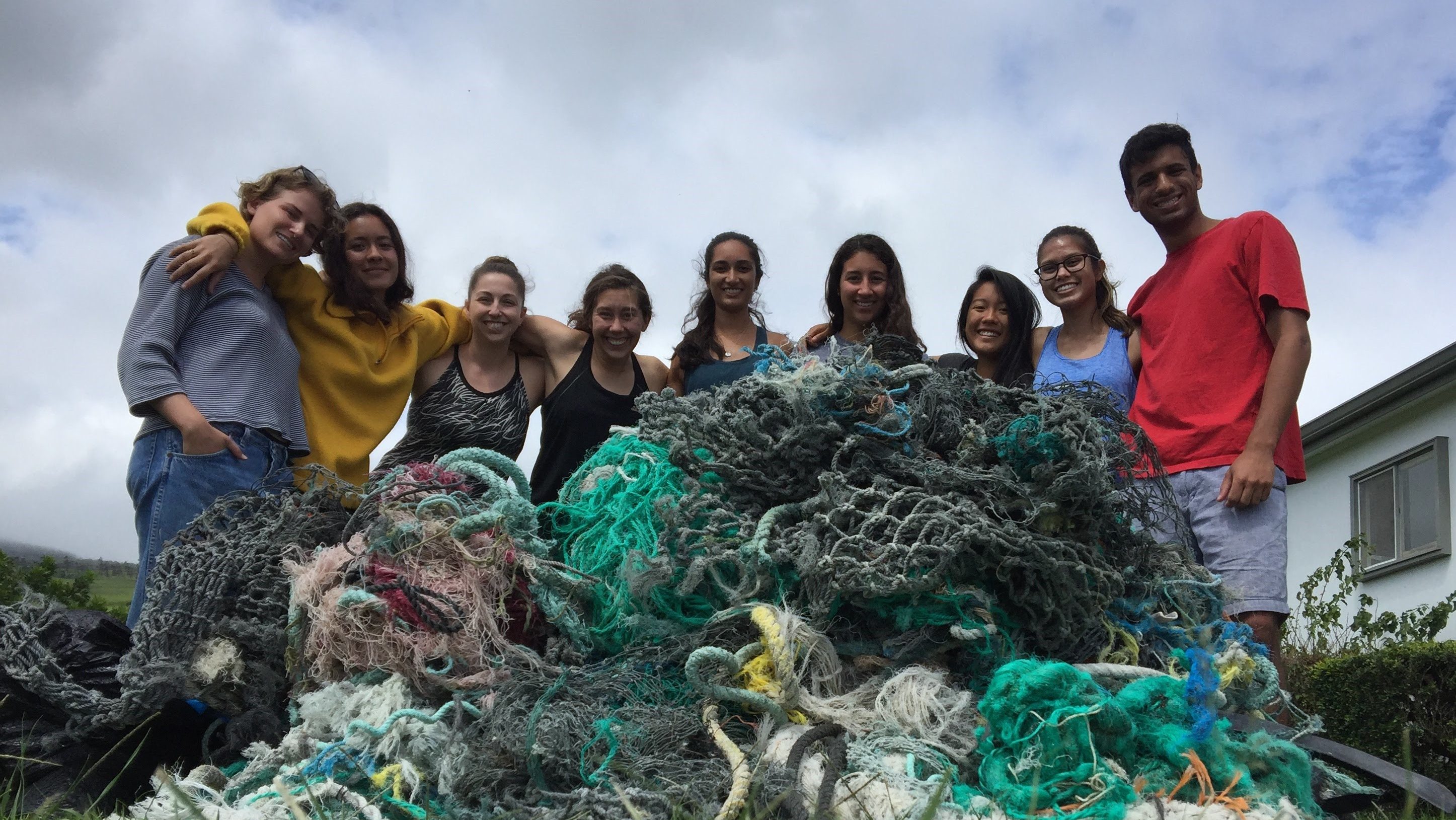 A photo of Samantha Burke and colleagues from the CORALS Program standing with trash they cleaned from a beach